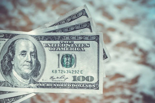 Girl holding money bill of 300 dollars on background of sea ocean waves with white foam and sand wet beach close-up. Hand wave sea ocean money dollars vacation. Concept finance money holiday traveling