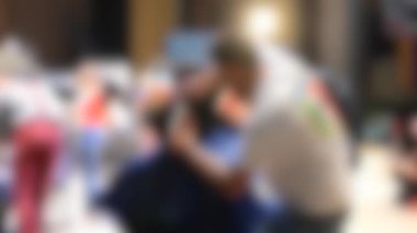 Arka plan bulanık. Erkek kuaförler erkek saçını yakından kesiyorlar.