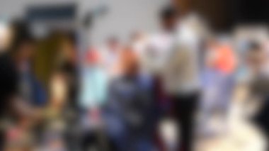 Arka plan bulanık. Erkek kuaförler erkek saçını yakından kesiyorlar.