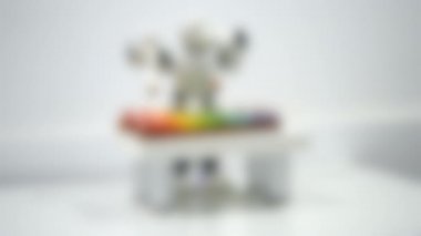 Arka plan bulanık. Küçük bir robot ksilofonda çalıyor. Yakından..