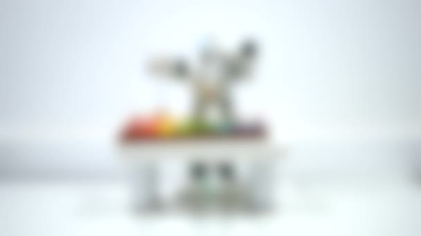 背景がぼやけている。小さなロボットが木琴の上で遊んでいる. — ストック動画