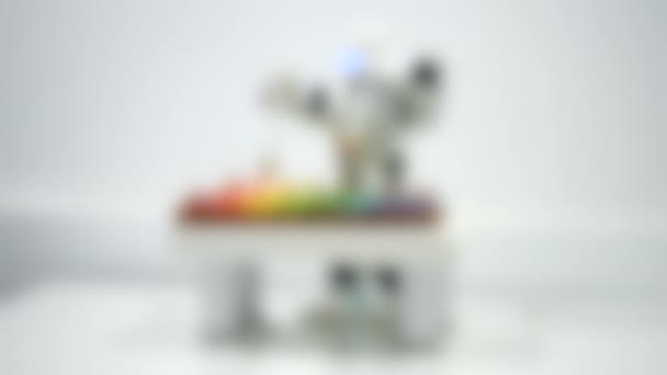 模糊的背景。一个小机器人在近旁的木琴上玩耍. — 图库视频影像