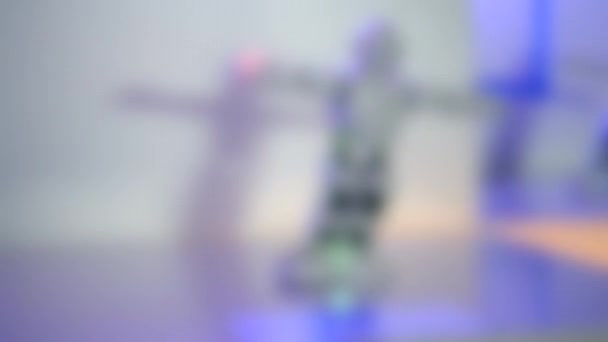 Unscharfer Hintergrund. Kleine Cyborg-Roboter, Humanoide mit Gesicht, leuchtende Augen — Stockvideo