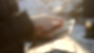 Arka plan bulanık. Sokakta güneşli bir karda tablette çalışan bir kız.