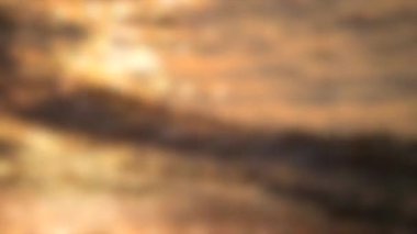 Arka plan bulanık. Güneş gün batımında denizin dalgalarına yansıyor.