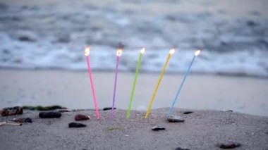 Mumlar, deniz kıyısındaki kumlu bir sahilde kumun içine yerleştirilmiş.