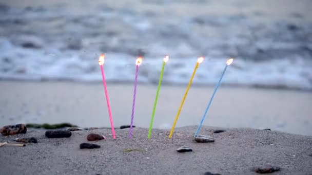 Velas insertadas en la arena en una playa de arena en la orilla del mar — Vídeo de stock