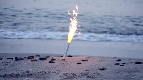 Vela-tinteiro de bolo com faíscas queimando na areia na praia de areia no mar oceano — Vídeo de Stock