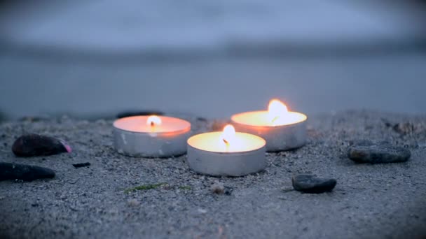 Kleine kaarsen aan de rand van zandstrand aan de kust naast zee golven — Stockvideo