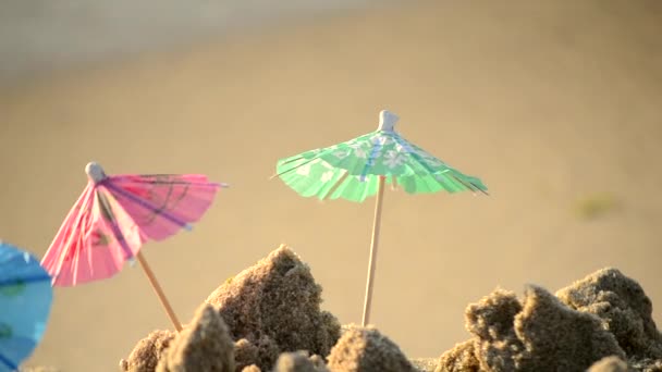 Små strandparaplyer av papper för ett cocktailställ på sandstranden — Stockvideo