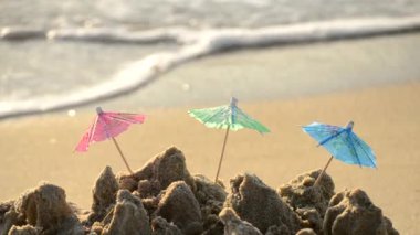 Kumsaldaki bir kokteyl standı için kağıttan yapılmış küçük plaj şemsiyeleri.