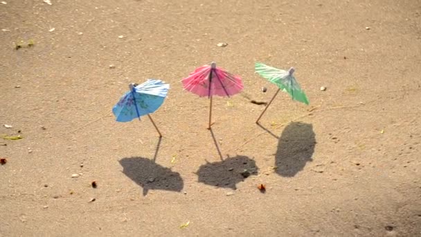 Pequenos guarda-sóis de praia feitos de papel para um coquetel na praia de areia — Vídeo de Stock