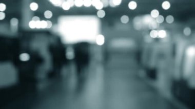 Binada yürüyen insanlar. Duvarları, zemini, tavan lambaları olan bir bina. İçerideki insanların siluetleri. Bir sürü insan yürüyor. Erkekler ve kadınlar uzun salonda. Sergi merkezi. Bulanık arkaplan