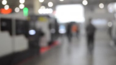 Binada yürüyen insanlar. Duvarları, zemini, tavan lambaları olan bir bina. İçerideki insanların siluetleri. Bir sürü insan yürüyor. Erkekler ve kadınlar uzun salonda. Sergi merkezi. Bulanık arkaplan