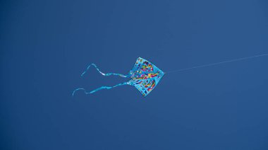 Mavi gökyüzünde uçan renkli bir uçurtma