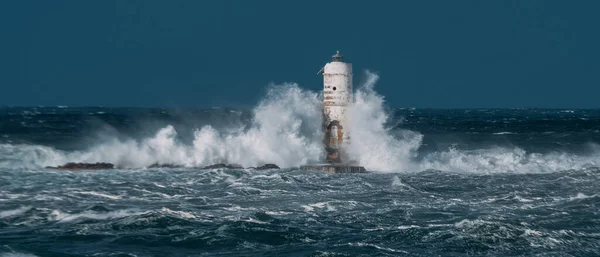 The lighthouse of the Mangiabarche shrouded by the waves of a mistral wind storm