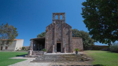 Oschiri 'de açık mavi gökyüzünün altında çan gable ile Romen taş kilise cephesi