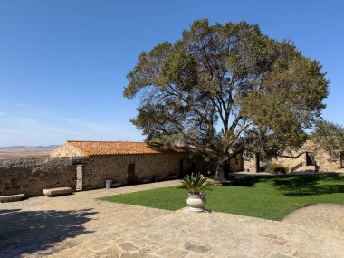 Avluda taş kilisesi ve patikası olan büyük bir karaağaç var.