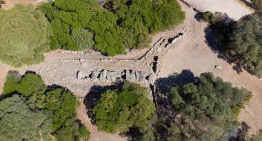 Olbia yakınlarında ağaçlar ve kuru manzarayla çevrili tarih öncesi dev mezarları.