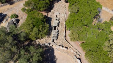 Olbia yakınlarında ağaçlar ve kuru manzarayla çevrili tarih öncesi dev mezarları.