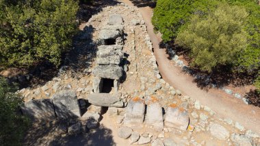 Olbia yakınlarında ağaçlar ve kuru manzarayla çevrili tarih öncesi dev mezarları.