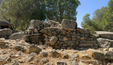 Olbia yakınlarında ağaçlar ve kuru manzarayla çevrili tarih öncesi dev mezarları.