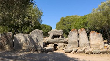 Olbia yakınlarında ağaçlar ve kuru manzarayla çevrili tarih öncesi dev mezarları.