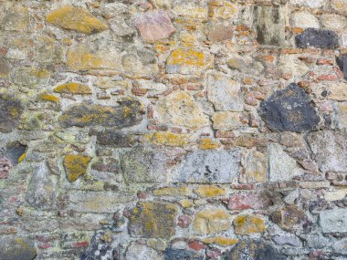 Çok renkli doğal kayalar ve havan topuyla taşralı taş duvar.