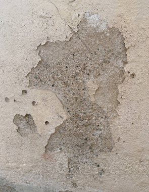 Çatlakları, soyulmuş katmanları ve açıkta kalmış tuğlaları gösteren çürüyen alçı duvarın yakın çekimi