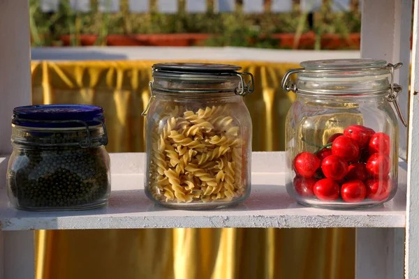 Show piece of pasta cherry and pulses in glass container