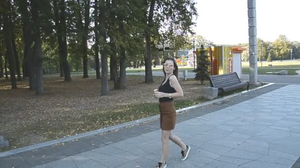 Женщина гуляет в городском парке и ест мороженое — стоковое видео