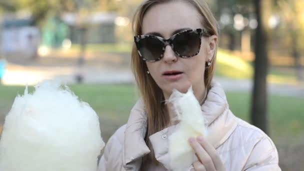 Блондинка їсть бавовняні цукерки в парку — стокове відео
