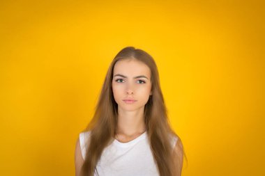 Güzel ve Genç sevinçle Fuarı saçlı kadın giyinmiş kayıtsızca, memnuniyeti kamera ile arıyorum. Stüdyo çekim yakışıklı güzel kadının sarı boş stüdyo duvar karşı izole.