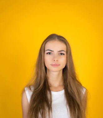 Güzel ve Genç sevinçle Fuarı saçlı kadın giyinmiş kayıtsızca, memnuniyeti kamera ile arıyorum. Stüdyo çekim yakışıklı güzel kadının sarı boş stüdyo duvar karşı izole.