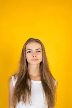 Güzel ve Genç sevinçle Fuarı saçlı kadın giyinmiş kayıtsızca, memnuniyeti kamera ile arıyorum. Stüdyo çekim yakışıklı güzel kadının sarı boş stüdyo duvar karşı izole.