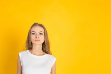 Güzel ve Genç sevinçle Fuarı saçlı kadın giyinmiş kayıtsızca, memnuniyeti kamera ile arıyorum. Stüdyo çekim yakışıklı güzel kadının sarı boş stüdyo duvar karşı izole.