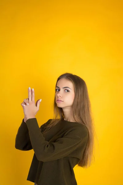 Mooie vrouw in trui is het verbergen van hand aan de orde gesteld en waait op vinger pistool — Stockfoto