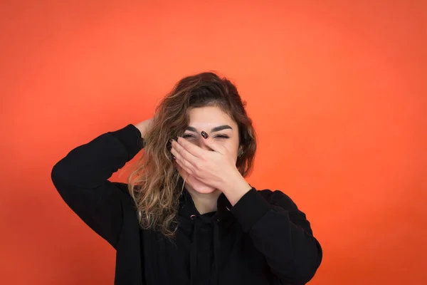 Menina bonita com cabelo encaracolado em uma camiseta preta em um fundo vermelho — Fotografia de Stock