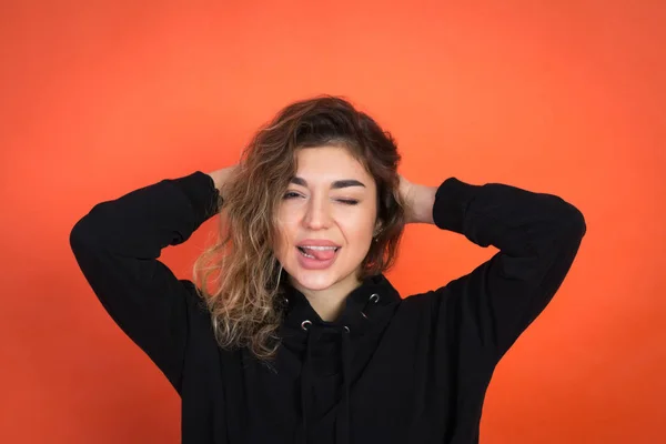 Menina bonita com cabelo encaracolado em uma camiseta preta em um fundo vermelho — Fotografia de Stock