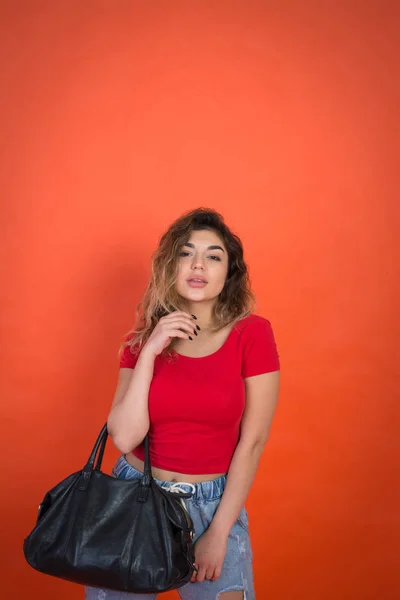 Lány göndör hajú, piros ing, fekete táska piros háttér — Stock Fotó
