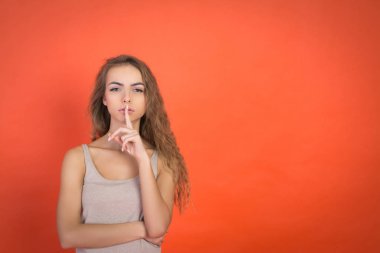 Dudaklar ve sessizlik yapıyor güzel genç kızın tss jest kırmızı arka plan ile boşaltmak izole işareti