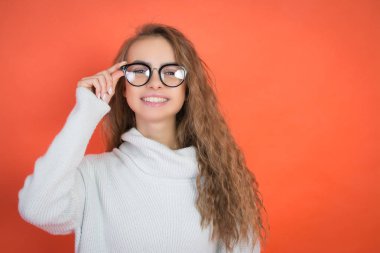 gözlük ve kırmızı bir arka plan üzerinde beyaz bir kazak güzel bir genç kız portresi