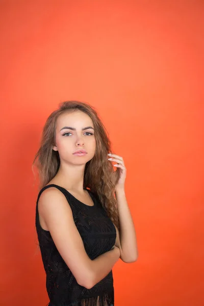 Модная молодая девушка позирует в студии на красном фоне — стоковое фото