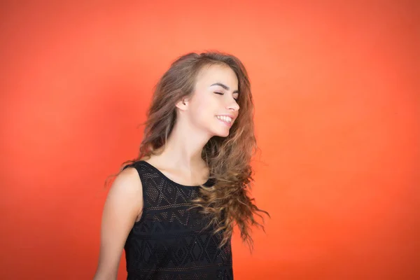 Modieuze jong meisje poseren in de studio op een rode achtergrond — Stockfoto