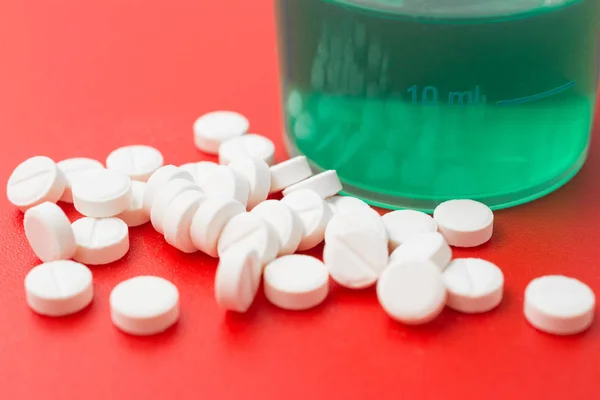 handful of cold pills antibiotic on a red background