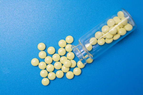 Tabletas de preparaciones sedantes en una botella de vidrio sobre un fondo azul — Foto de Stock
