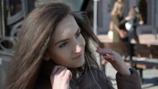 Портрет молодої милої привабливої молодої дівчини на фоні міських вулиць прослуховування музики з навушниками — стокове відео