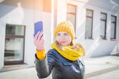 Sarı örme şapka içinde güzel kadın kendini cep telefonunda çekiyor