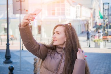 Güzel genç esmer gülümseyen selfi Avrupa şehirde sokak alarak uzun saçlı