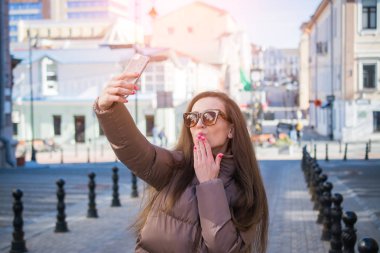 Güzel genç kadın bir selfie için poz ise bir hava öpücük esiyor